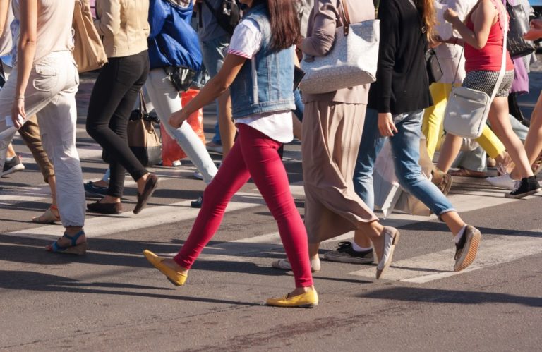 feet of young pedestrians walking on the crosswalk on summer day