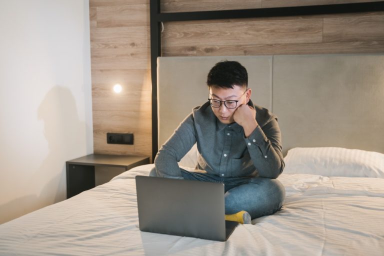 man in bed using his laptop